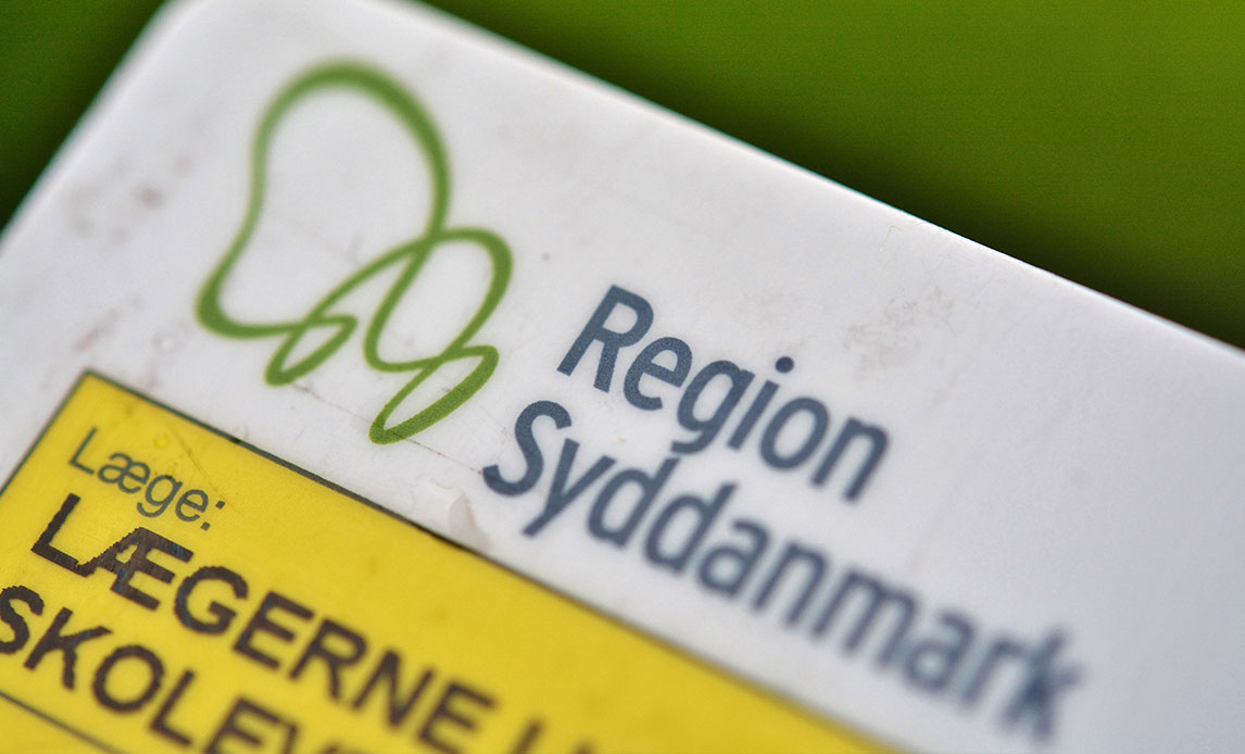 Nærbillede af øverste venstre hjørne af et gult sygesikringskort med logoet fra Region Syddanmark. Tekst siger Lægerne i...