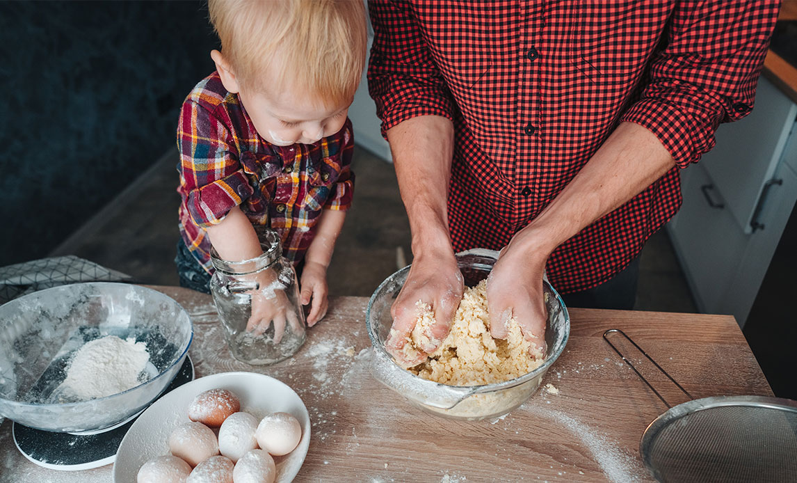 En voksen mand og en lille dreng er i gang med at bage.