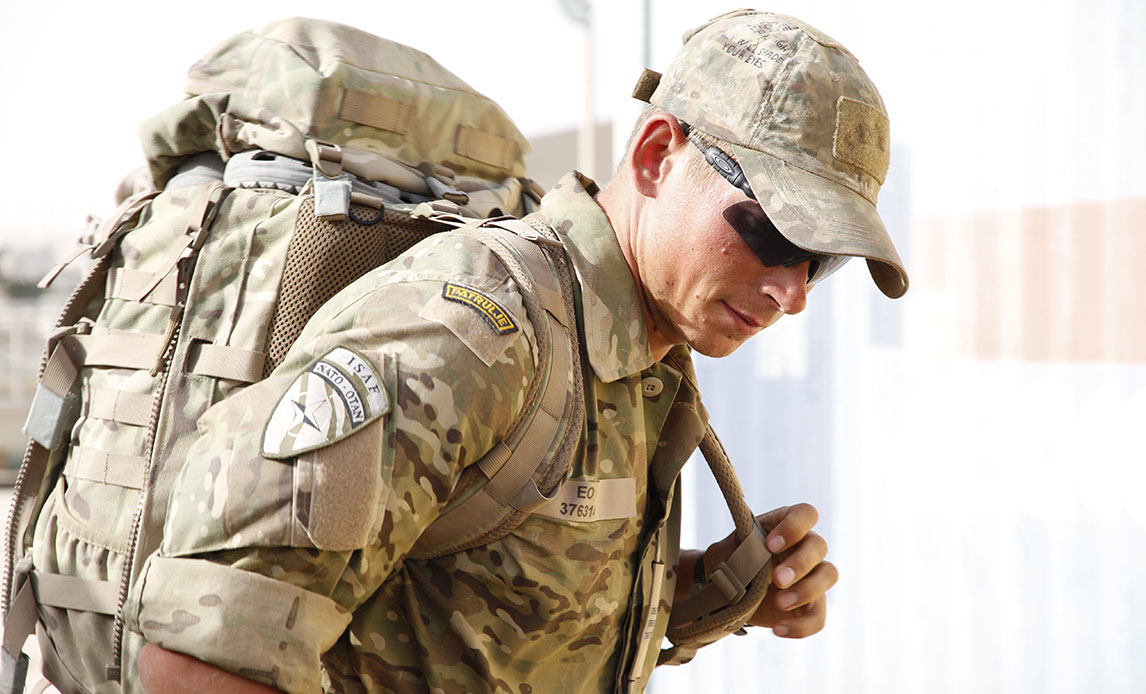 Soldat i uniform med rygsæk og kasket på samt mørke solbriller, man ikke kan se igennem.